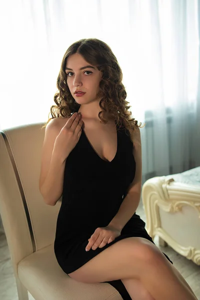 Gorgeous lady in long black dress in hotel room