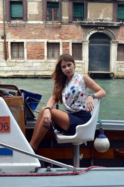 Chica joven con falda azul y camisa de flores mientras monta un barco en Venecia —  Fotos de Stock