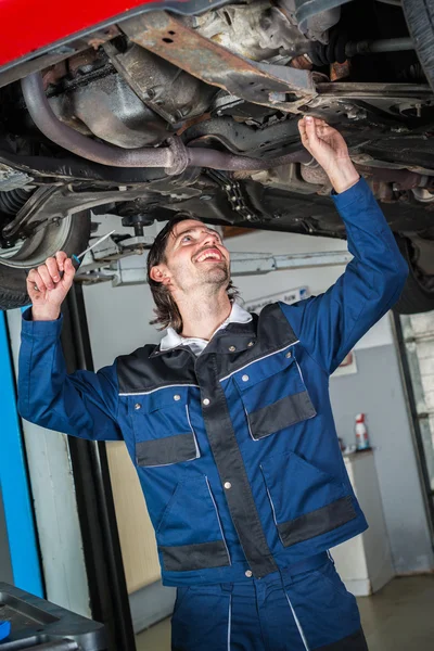 Mecânico verificando o estado de um carro levantado — Fotografia de Stock