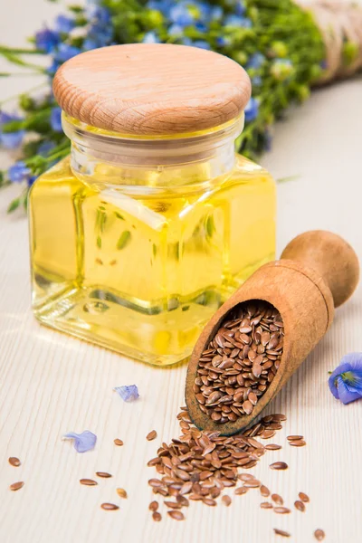 Linseed oil, flax seeds, and flowers on a light background. — Stock Photo, Image