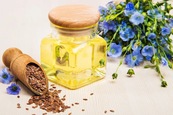 Linseed oil, flax seeds, and flowers on a light background. — Stock Photo, Image