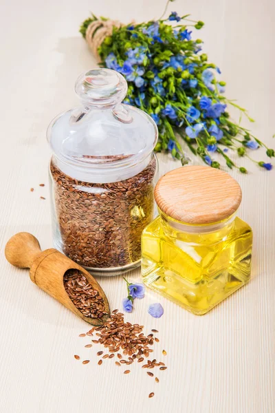 Льняное масло, семена льна и цветы на светлом фоне . — стоковое фото