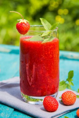 Eski bir mavi ahşap yüzey üzerinde çilek smoothies