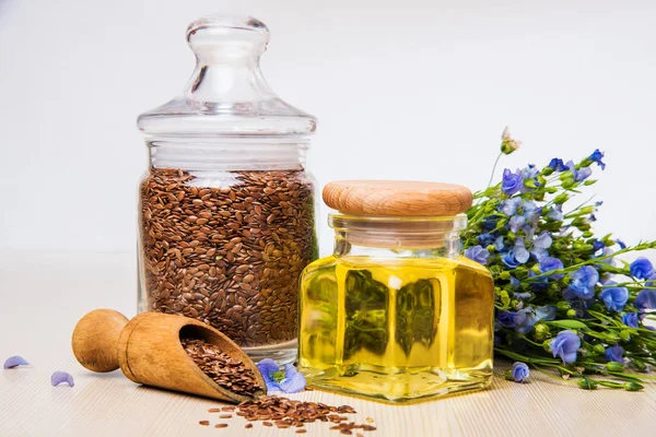 Leinöl, Leinsamen und Blumen auf hellem Hintergrund. — Stockfoto