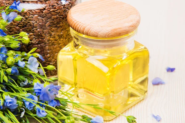 Aceite de linaza, semillas de lino y flores sobre un fondo claro . — Foto de Stock