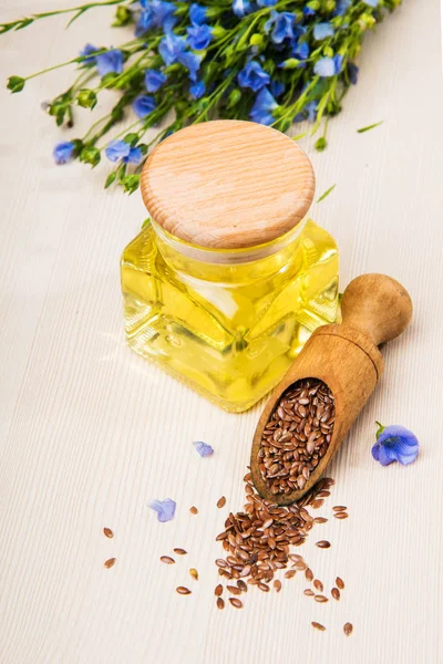 Льняное масло, семена льна и цветы на светлом фоне . — стоковое фото