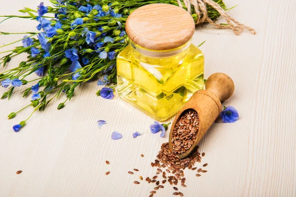 Linseed oil, flax seeds, and flowers on a light background. — Stock Photo, Image