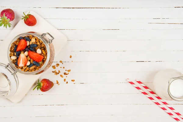 Homemade granola in a glass jar on a white table. Healthy food. — Stock Photo, Image