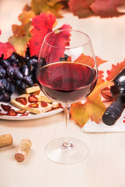 Natura morta con una bottiglia e un bicchiere di vino rosso, uva e cioccolato con fragole — Foto Stock