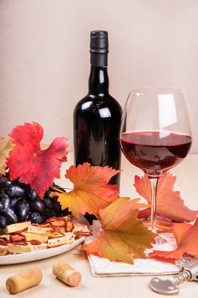 Natura morta con una bottiglia e un bicchiere di vino rosso, uva e cioccolato con fragole — Foto Stock