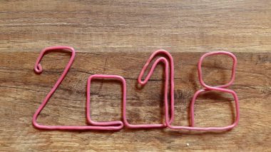ahşap arka plan üzerinde titreyen şekil 8, pembe bir kabloyla 2018 numarası