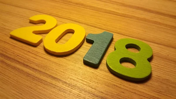 Holzfarbige Zahlen, die die Zahl 2018 bilden, für das neue Jahr 2018 auf einem Holzgrund. — Stockfoto