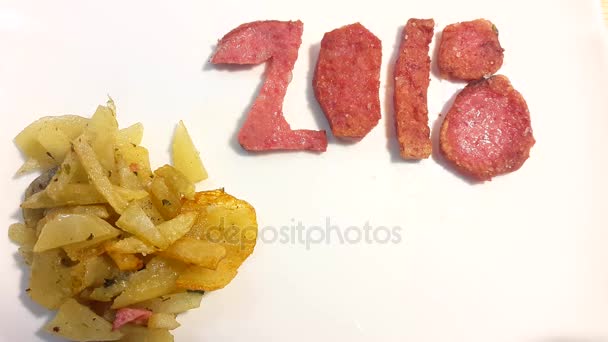 Wurst in Form von Zahl 2018 mit Bratkartoffeln und Petersilie auf weißem Teller — Stockvideo