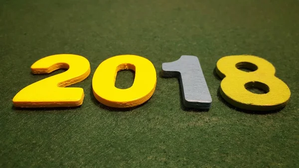 Кольорові фігури, щоб сформувати номер 2018 року на зеленому фоні — стокове фото
