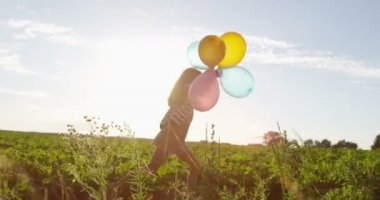 Koşu ve küçük kız havayla çalışan yeşil alanına Sunset yavaş hareket sırasında balonlar