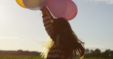 Küçük kız hava balonu açık havada ağır çekimde elinde tutan gülümseyerek