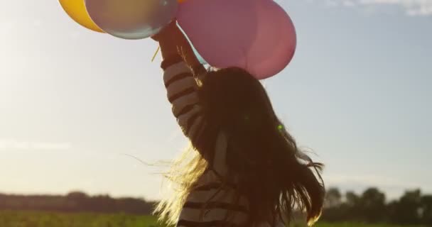 Glimlachend meisje lucht ballonnen bedrijf in handen buitenshuis in Slow Motion — Stockvideo