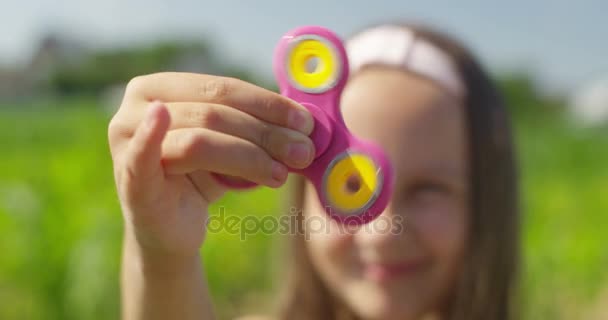 Close up de menina sorridente brincando com Spinner no campo no dia ensolarado — Vídeo de Stock