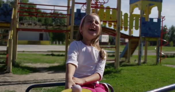 Kind mit Mutter auf Spielplatzkarussell in der Sommerpause — Stockvideo