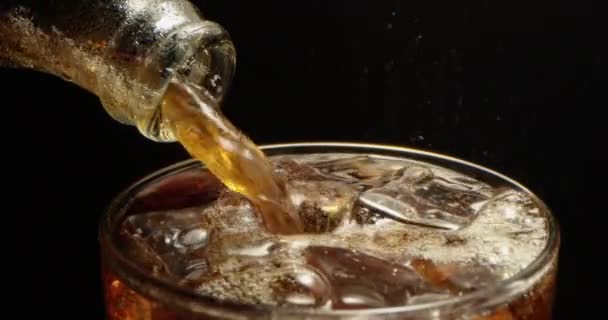 可乐正倒入一个装有冰块的杯子里 一个黑色背景的红葡萄酒大杯里 — 图库视频影像