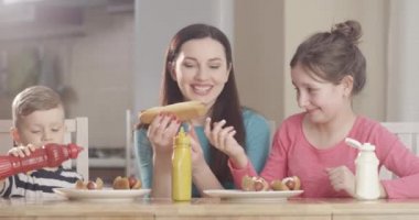 Aile Sosisli sandviç yapıyor ve birlikte vakit geçiriyorlar. Mutfak masasında yemek pişiriyorlar. Kırmızı Kamera 'da.