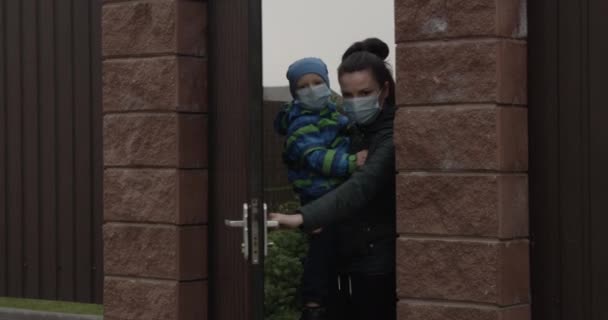顔のマスクを身に着けている子供の閉会ドアを持つ親コロナウイルスの流行による自己分離と社会的距離の概念 Covid — ストック動画