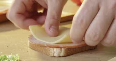 Jambonlu ve peynirli sandviçi marul ve tost ekmeğiyle hazırlıyorum.