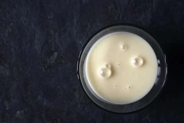 Leche condensada en el recipiente de vidrio en el fondo de piedra vista superior — Foto de Stock