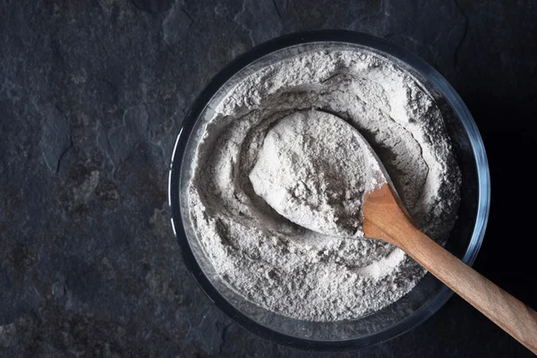 Harina en el cuenco de vidrio en la mesa de piedra vista superior — Foto de Stock