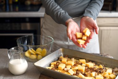 Patates dilimleri ve pastırma ile fırın tepsisinde peynir koyarak