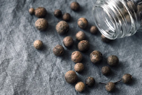 Allspice in de glazen pot op de grijze doek — Stockfoto