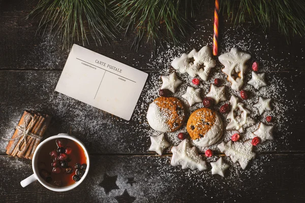 Рождественский бал с печеньем на деревянном фоне с открытками и ягодным чаем — стоковое фото
