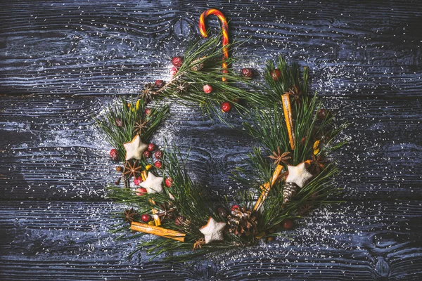 Corona de Navidad con galletas, bayas, especias en el fondo de madera — Foto de Stock