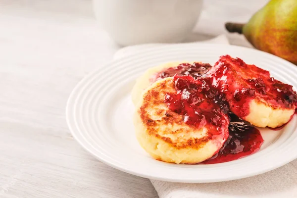 Cheesecakes med jordgubbssylt på en vit platta — Stockfoto
