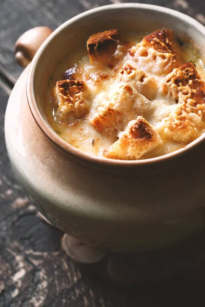 Луковый суп в керамическом горшке на деревянном столе — стоковое фото