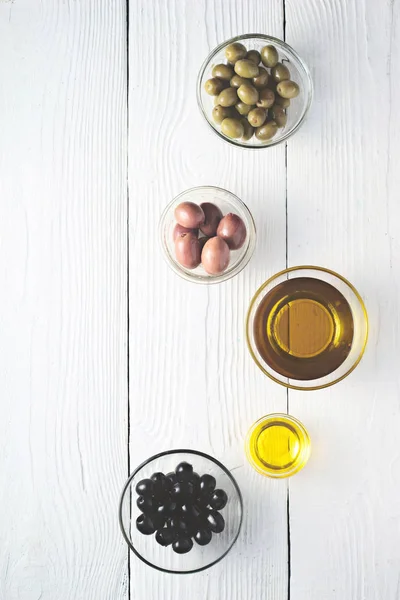 Zaitun dan minyak zaitun yang berbeda di atas meja putih — Stok Foto