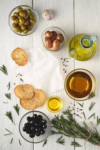 Aceite de oliva con pan y aceitunas se mezclan en la mesa de madera blanca vista superior — Foto de Stock