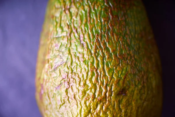 Avocado mit Reliefschale auf dem violetten Hintergrund — Stockfoto