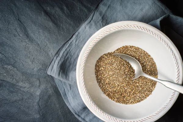 Chia seeds  in the white plate  with spoon on the dark stone table top view — Stock Photo, Image