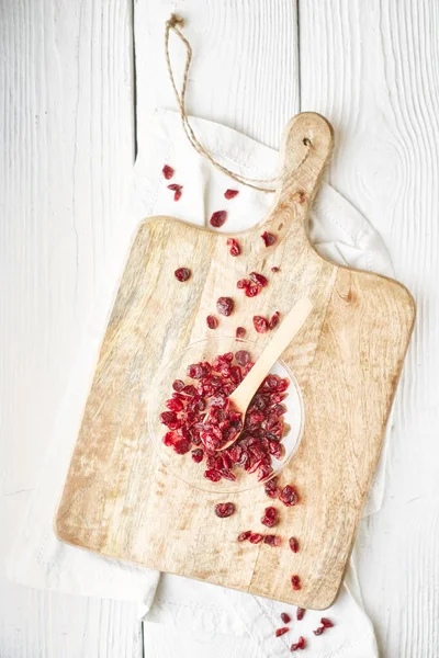 Cranberries secas na tigela de vidro na vista superior da mesa de madeira branca — Fotografia de Stock