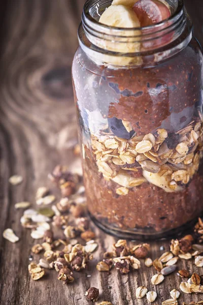 Chocolate chia pudding with oat flakes in the glass jar on the wooden table — Stock Photo, Image