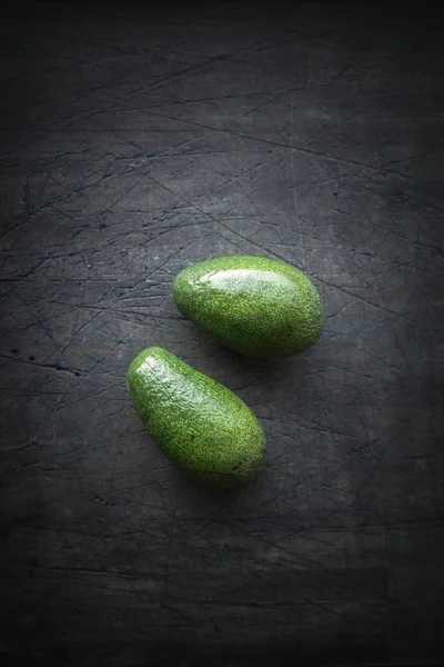 Avocado auf der dunkel zerkratzten Tischplatte — Stockfoto
