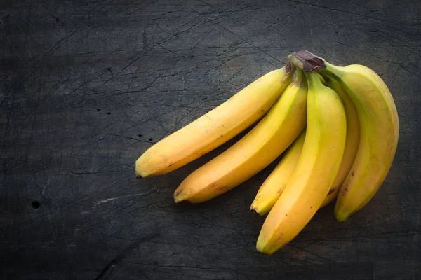 Bananenstrauß auf der dunkel zerkratzten Tischplatte — Stockfoto