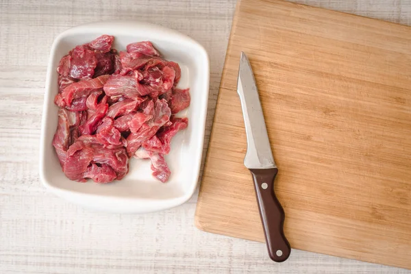 Carne cruda en rodajas con cuchillo en la parte superior de la mesa blanca —  Fotos de Stock