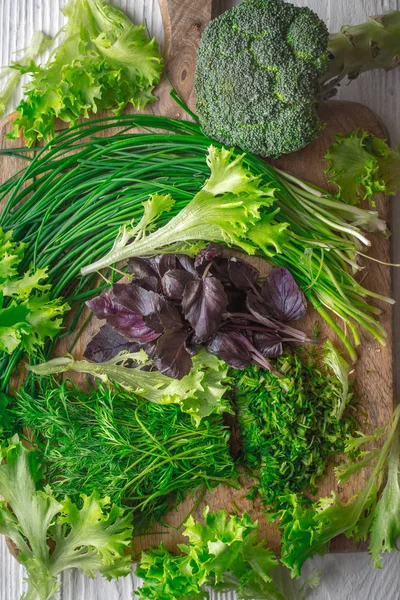 Brokoli, marul, fesleğen, soğan, dereotu kesme tahtası üzerinde — Stok fotoğraf