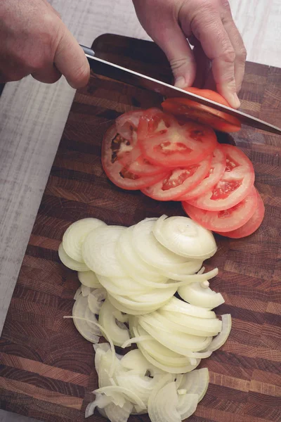 Cortar los tomates y la cebolla en la tabla de madera vertical — Foto de Stock