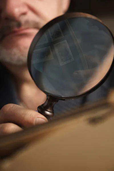 Magnifying glass with reflective stamps in the man`s hand — Stock Photo, Image