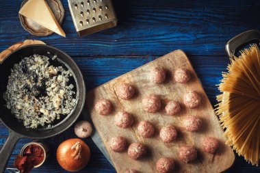 Çiğ köfte ve mavi ahşap arka plan üzerinde farklı malzemelerle spagetti