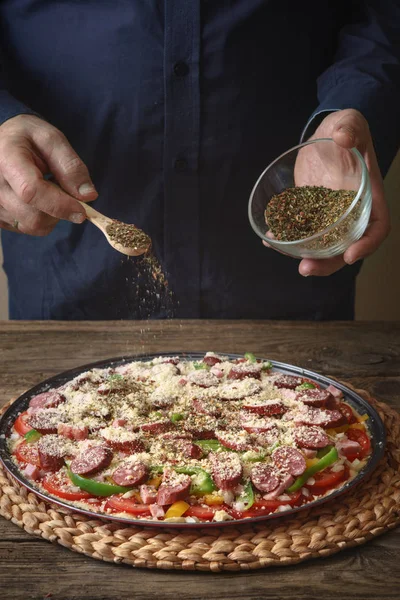 Мужчина посыпает пиццей со специями от стеклянной тарелки — стоковое фото