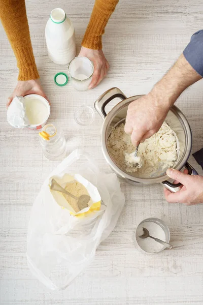 Man and woman makes the dough in the pan on the white table — Stock Photo, Image